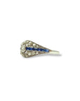 Profil d’une bague ancienne Art Déco en or blanc 18 carats, révélant une monture en dôme ajouré sertie de diamants et de saphirs.