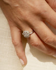 Bague en or blanc 18 carats et diamants en forme de trèfle, portée sur une main.
