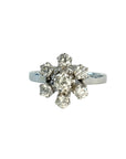 Bague en or gris 18 carats sertie de sept diamants taille brillant en serti griffe formant une fleur sur une monture ajourée, bijou raffiné et lumineux.