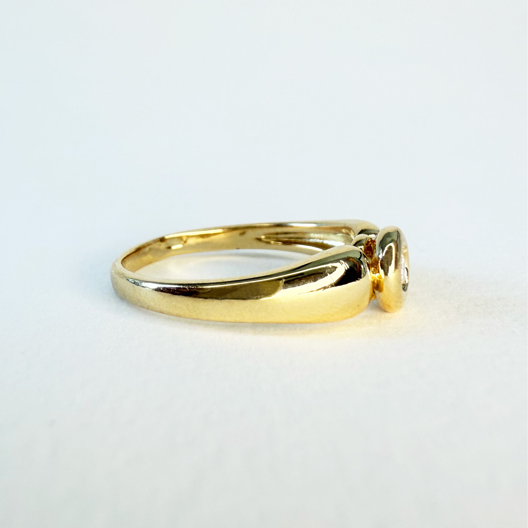 Bague solitaire en or jaune 18 carats sertie d’un diamant en serti clos d’environ 0,07 carat, bijou raffiné symbole d’amour éternel et d’engagement.