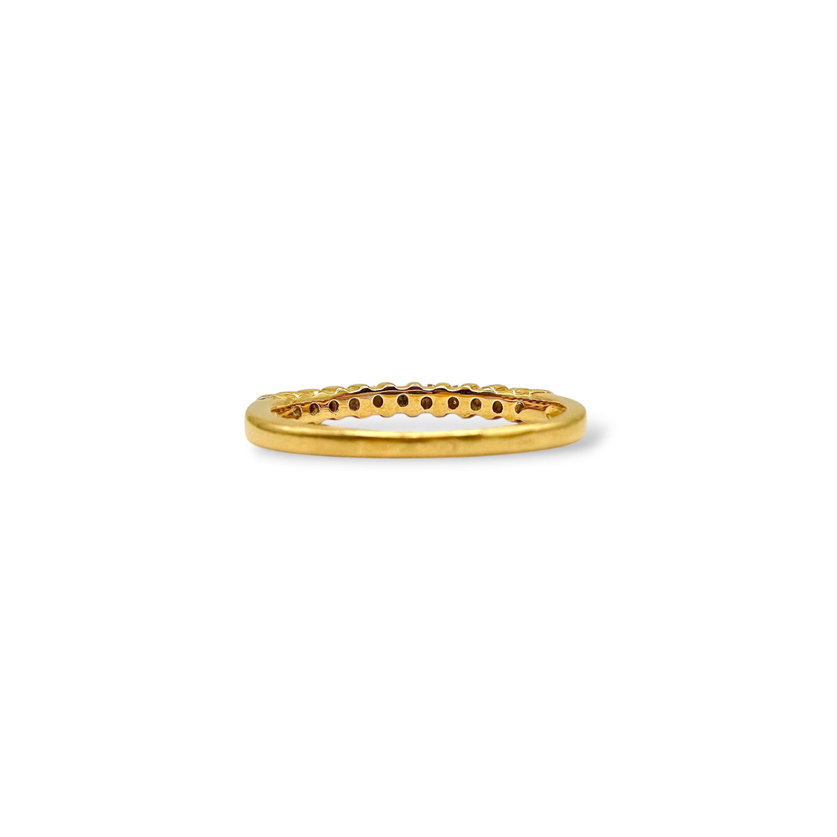 Détail du serti grain d’une demi-alliance en or jaune 18 carats, mettant en valeur une rangée de petits diamants.