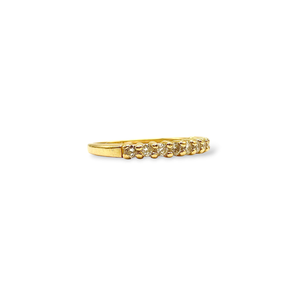 Détail du serti grain d’une demi-alliance en or jaune 18 carats, mettant en valeur une rangée de petits diamants.