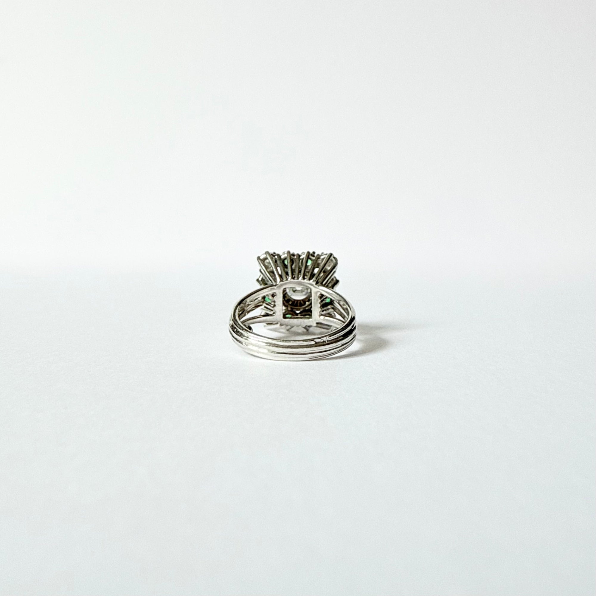Bague marguerite en or gris 18 carats sertie d'un diamant taille émeraude entouré d'émeraudes et de diamants, vue de l'interieur.