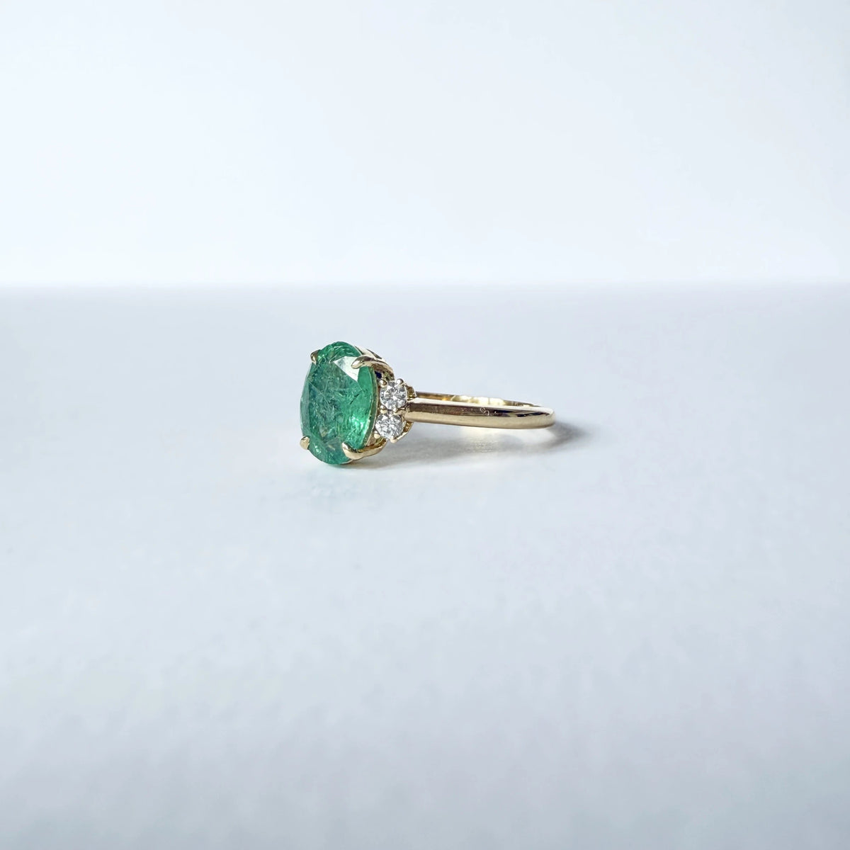 Bague émeraude ovale non chauffé flanquée de quatre diamants taille brillant sur ue monture en or jaune 18 carats.