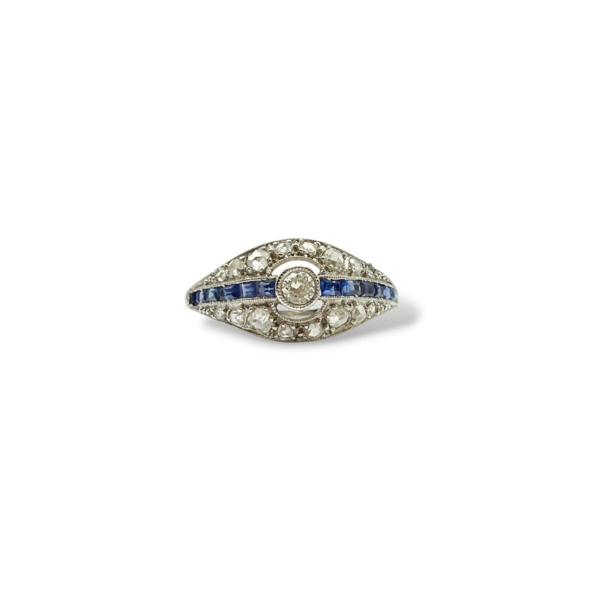 Bague Art Déco en or blanc 750 millièmes, avec diamant central entouré de diamants taille rose et ligne de saphirs calibrés bleu profond.