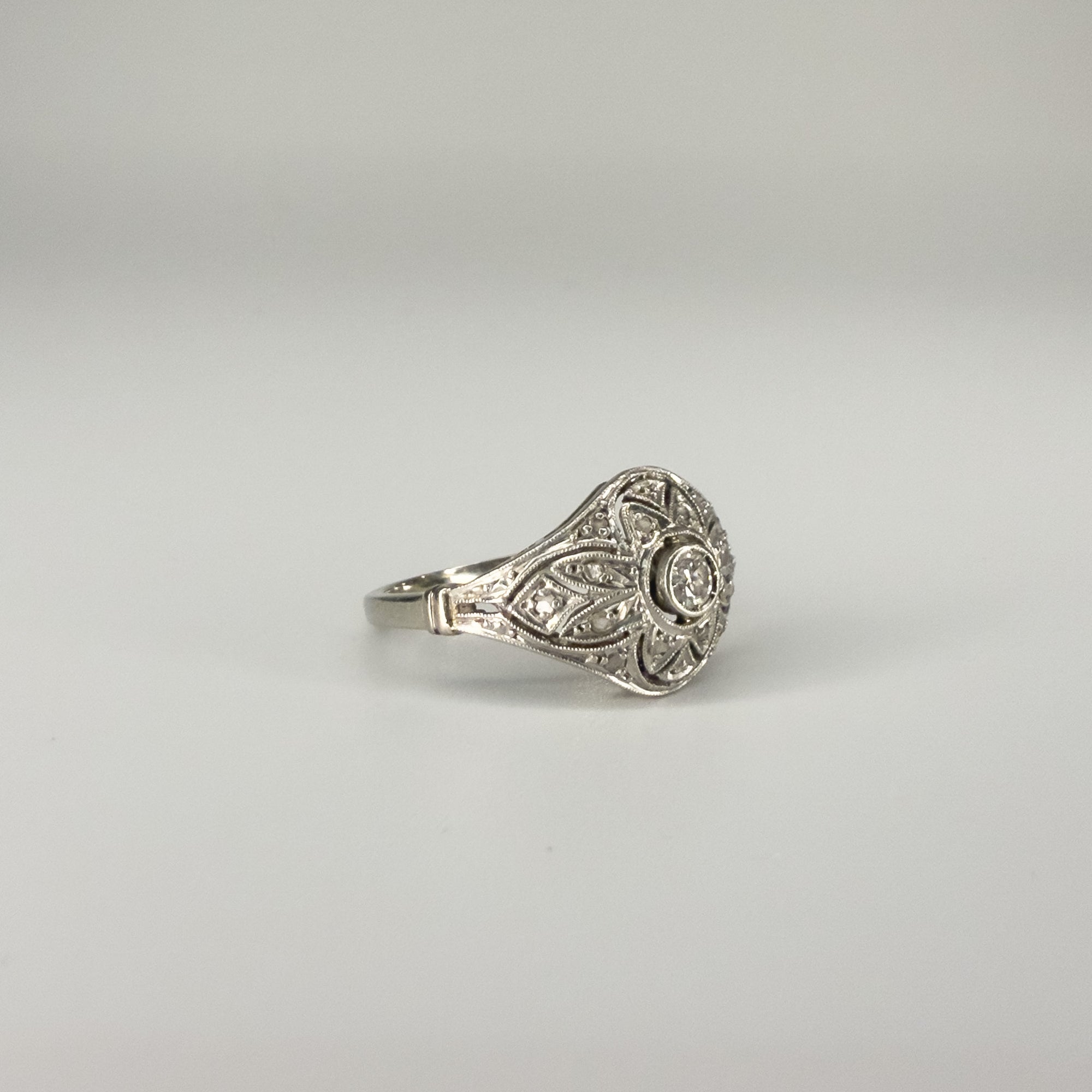 Bague Art Déco en platine ajouré ornée d’un diamant central d’environ 0,1 carat, bijou ancien géométrique de qualité, pièce de joaillerie d’occasion élégante et raffinée.