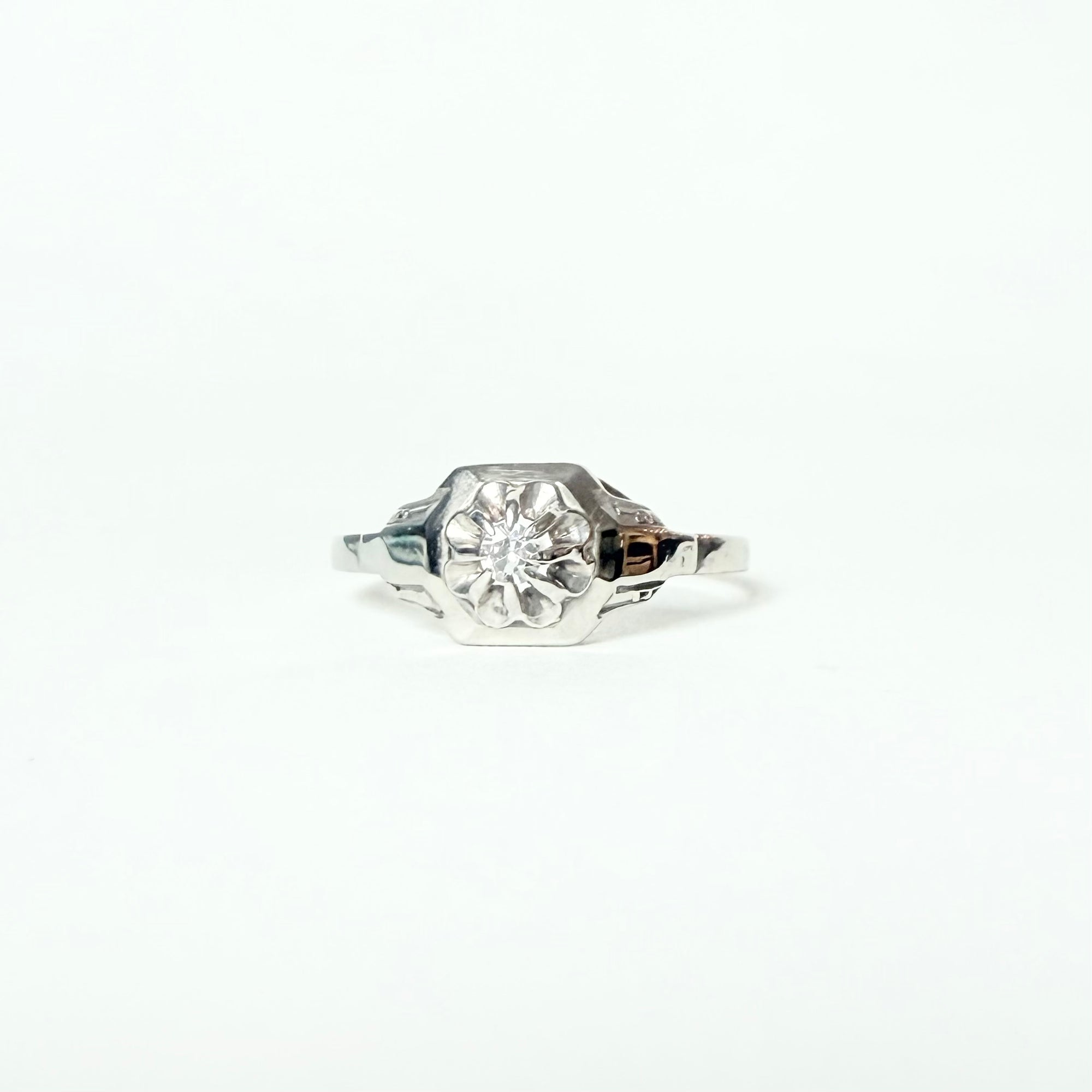 Bague solitaire Art déco en or blanc 18 carats, mettant en valeur un diamant taille brillant serti en griffes, délicatement posé sur un chaton octogonal pour une allure géométrique et élégante.