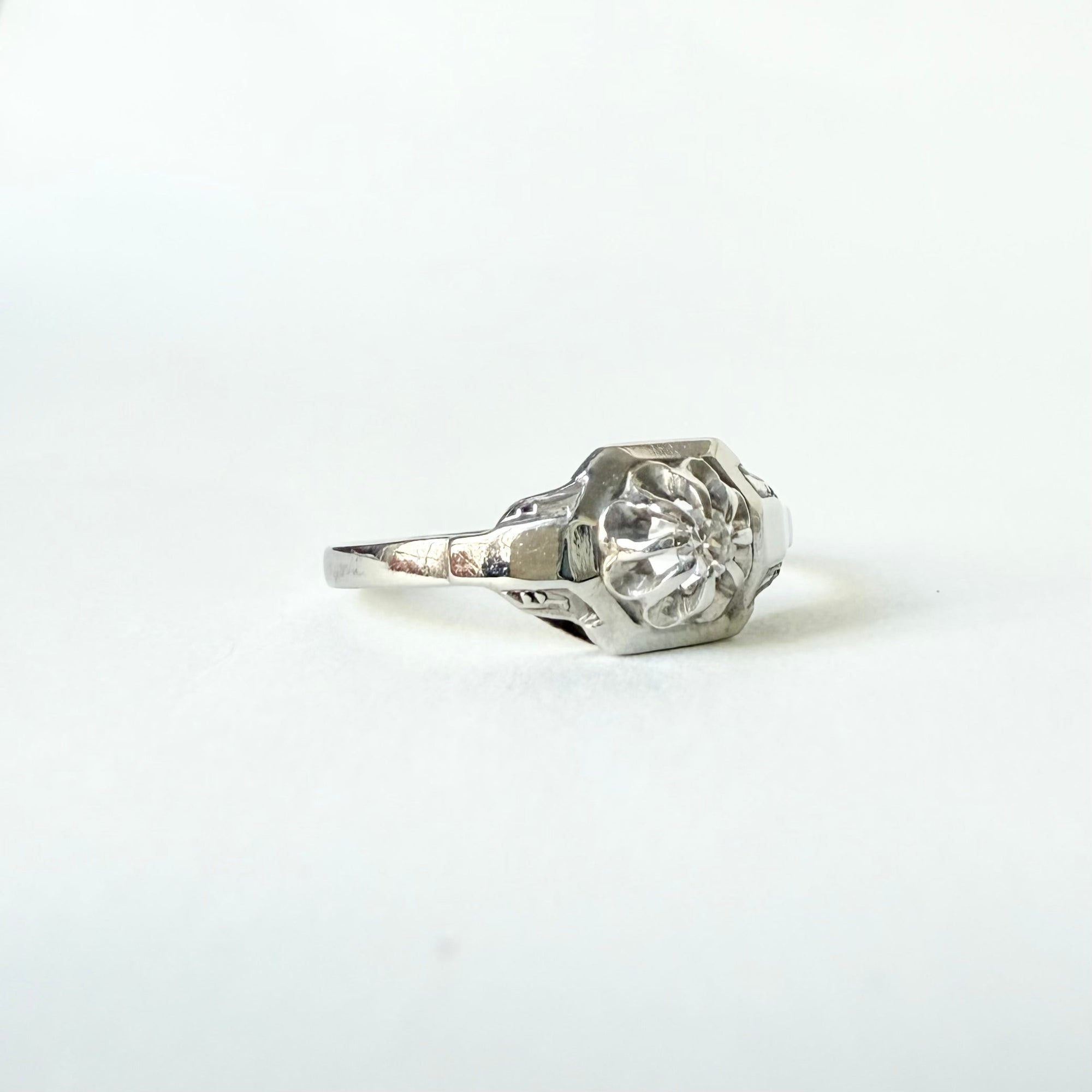 Bague solitaire Art déco en or blanc 18 carats, mettant en valeur un diamant taille brillant serti en griffes, délicatement posé sur un chaton octogonal pour une allure géométrique et élégante.