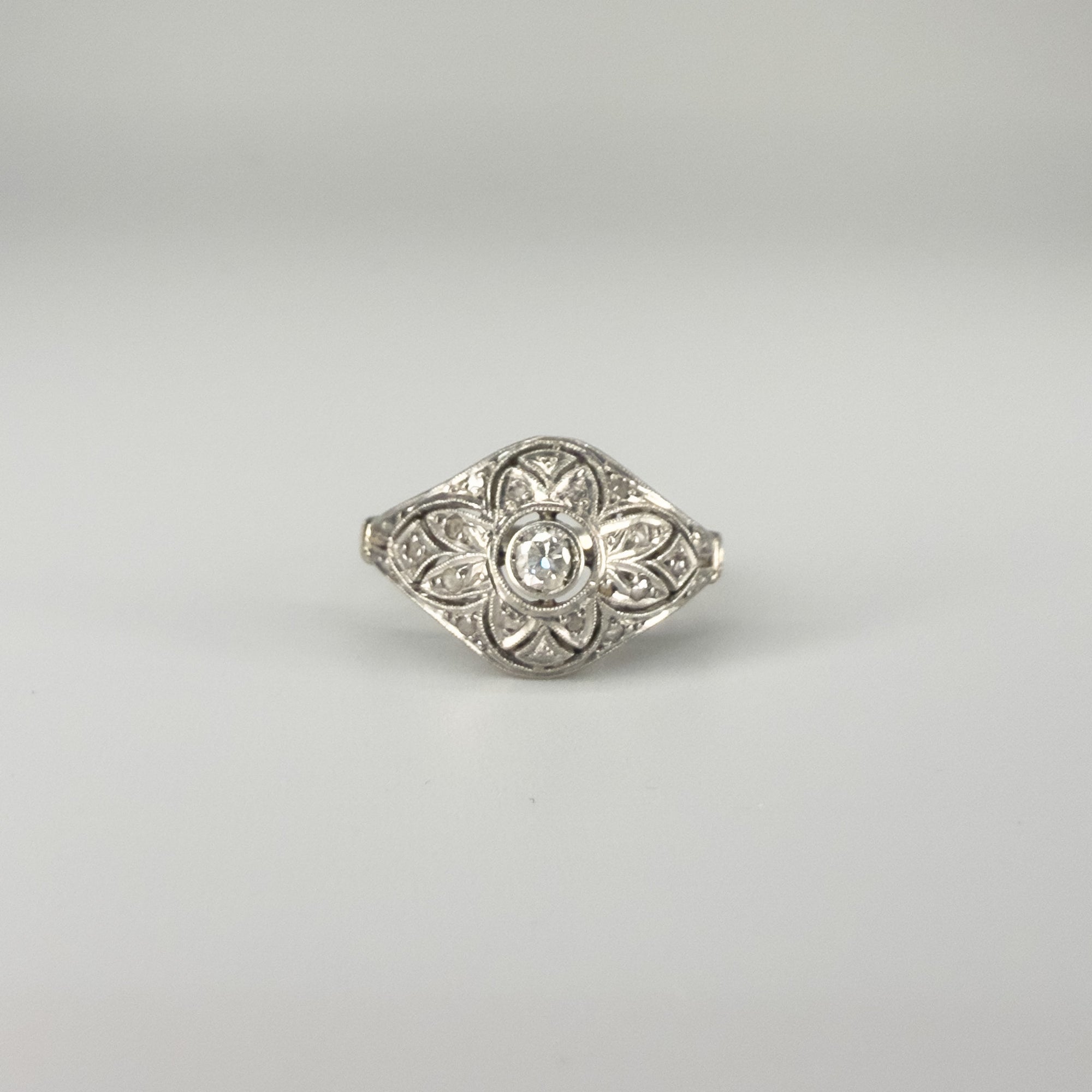 Bague Art Déco en platine ajouré ornée d’un diamant central d’environ 0,1 carat, bijou ancien géométrique de qualité, pièce de joaillerie d’occasion élégante et raffinée.