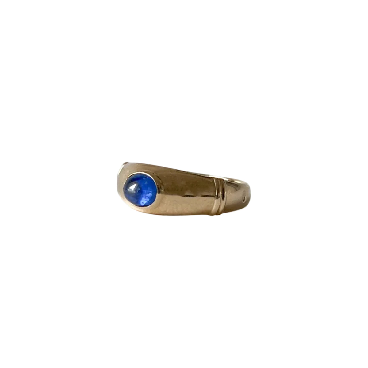 Détail du saphir cabochon bleu translucide serti sur une bague en or jaune 18 carats