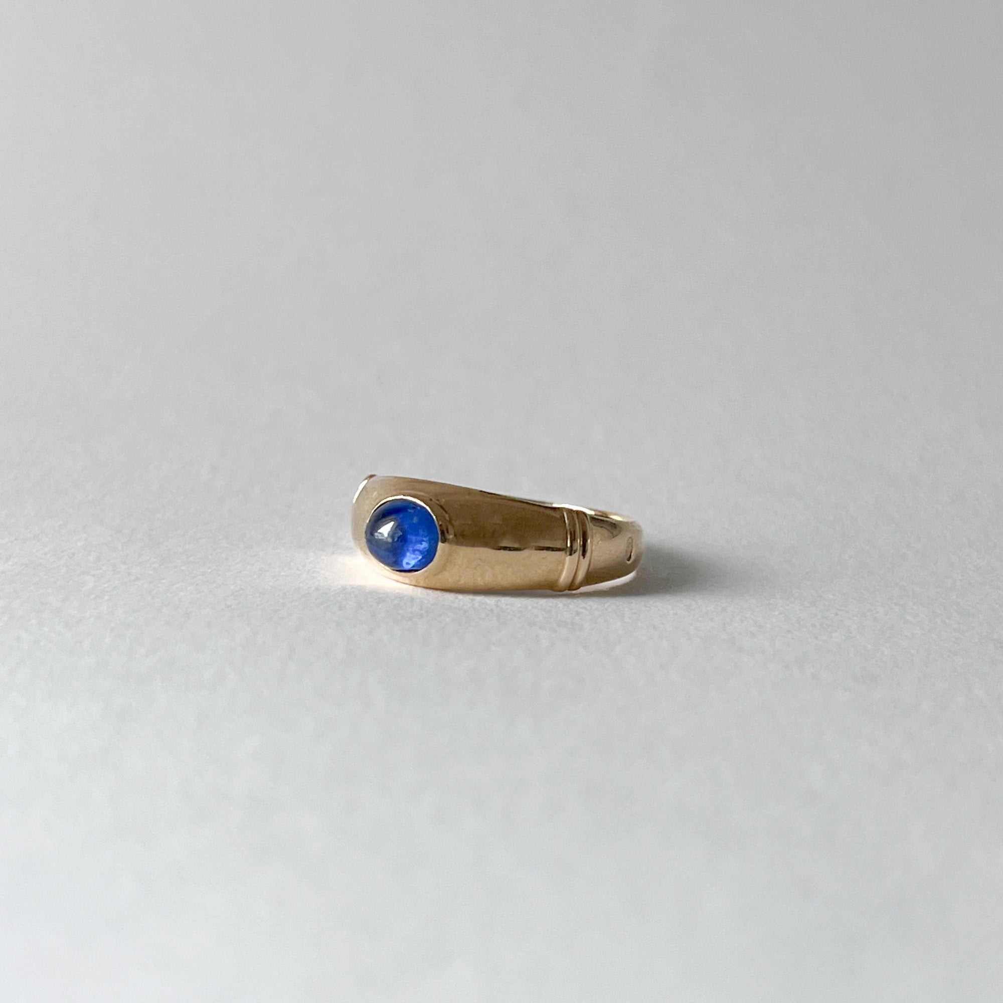Détail du saphir cabochon bleu translucide serti sur une bague en or jaune 18 carats