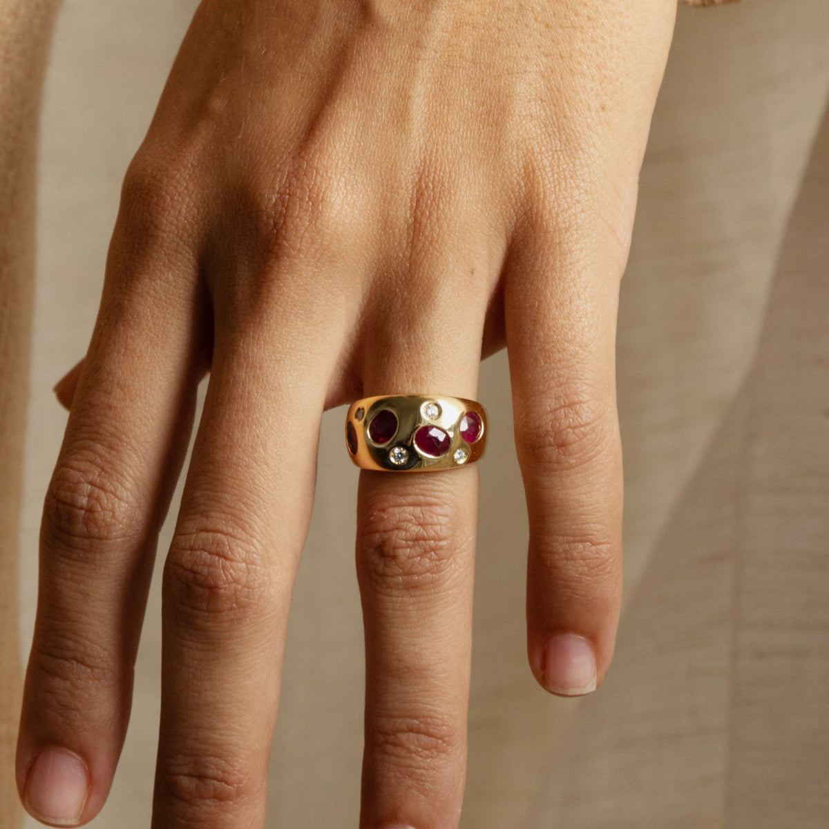 Bague bandeau vintage en or jaune sertie de rubis et de diamants portée au doigt