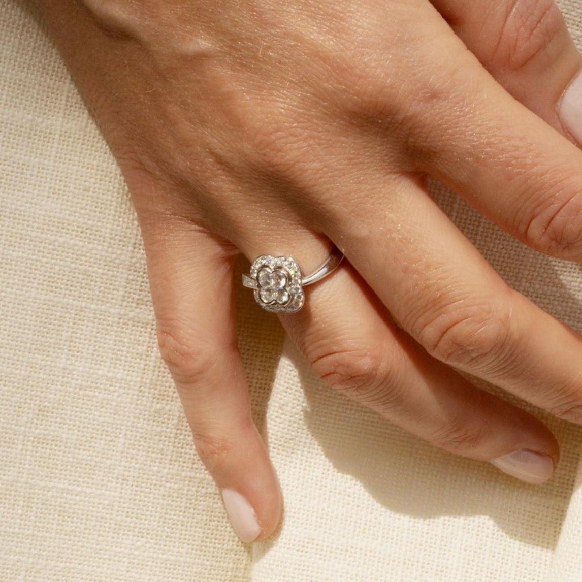 Bague en or blanc 18 carats et diamants en forme de trèfle, portée sur une main.