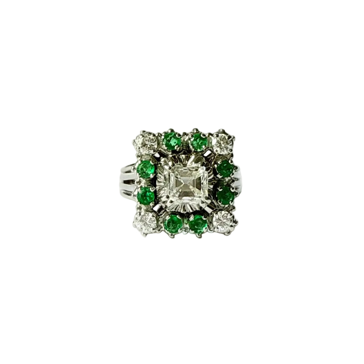 Bague marguerite en or gris 18 carats sertie d'un diamant taille émeraude entouré d'émeraudes et de diamants, vue de face.