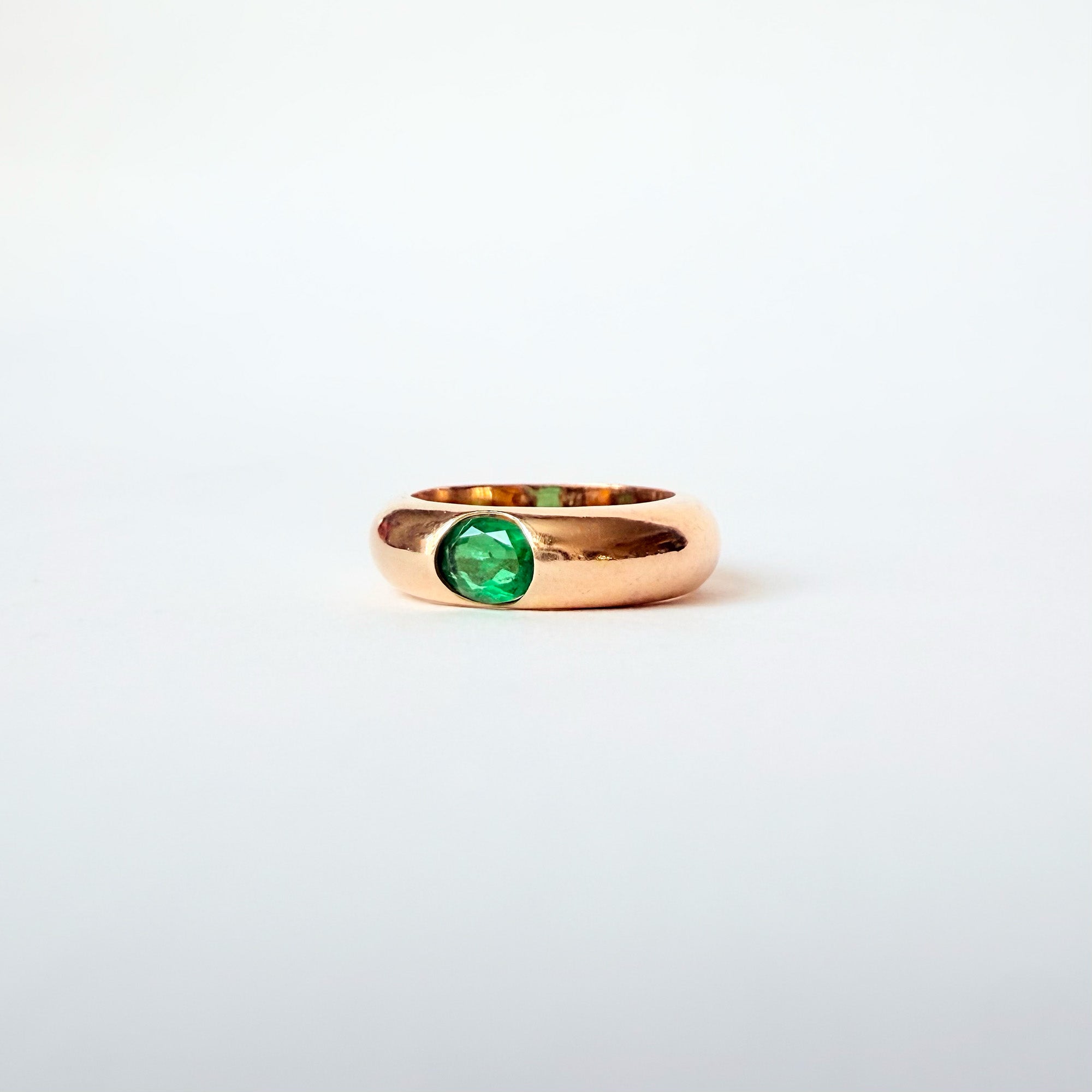 Vue de profil d’une bague jonc en or jaune 18 carats sertie d’une émeraude naturelle de 0,4 carat