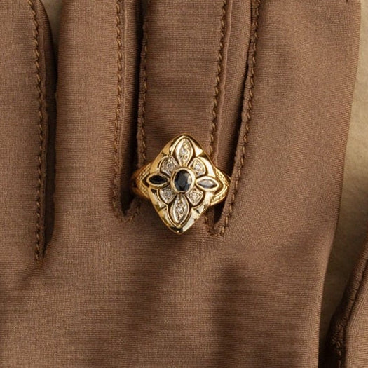 Bague navette en or jaune et or gris 18 carats sertie de saphirs et de diamants taille brillant. Porté sur un gant.