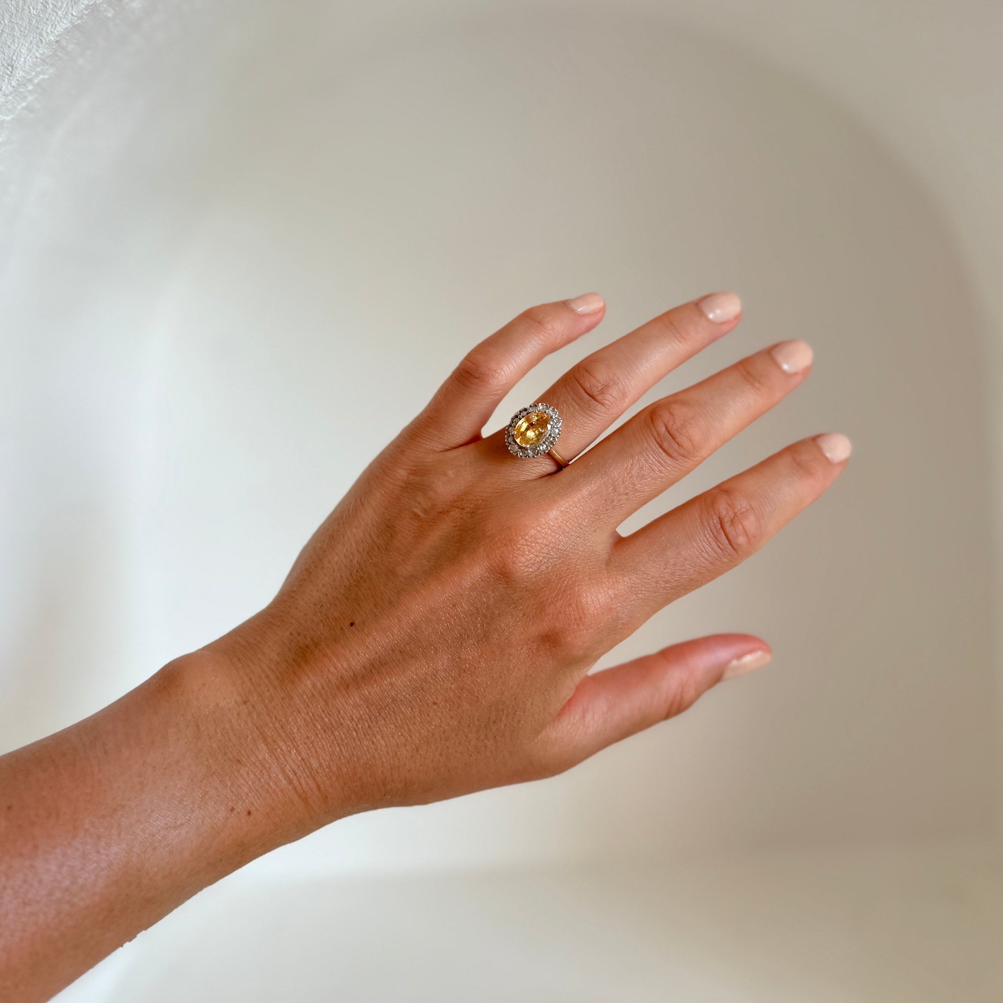 Bague marguerite en or 18 carats portée au doigt avec saphir jaune naturel