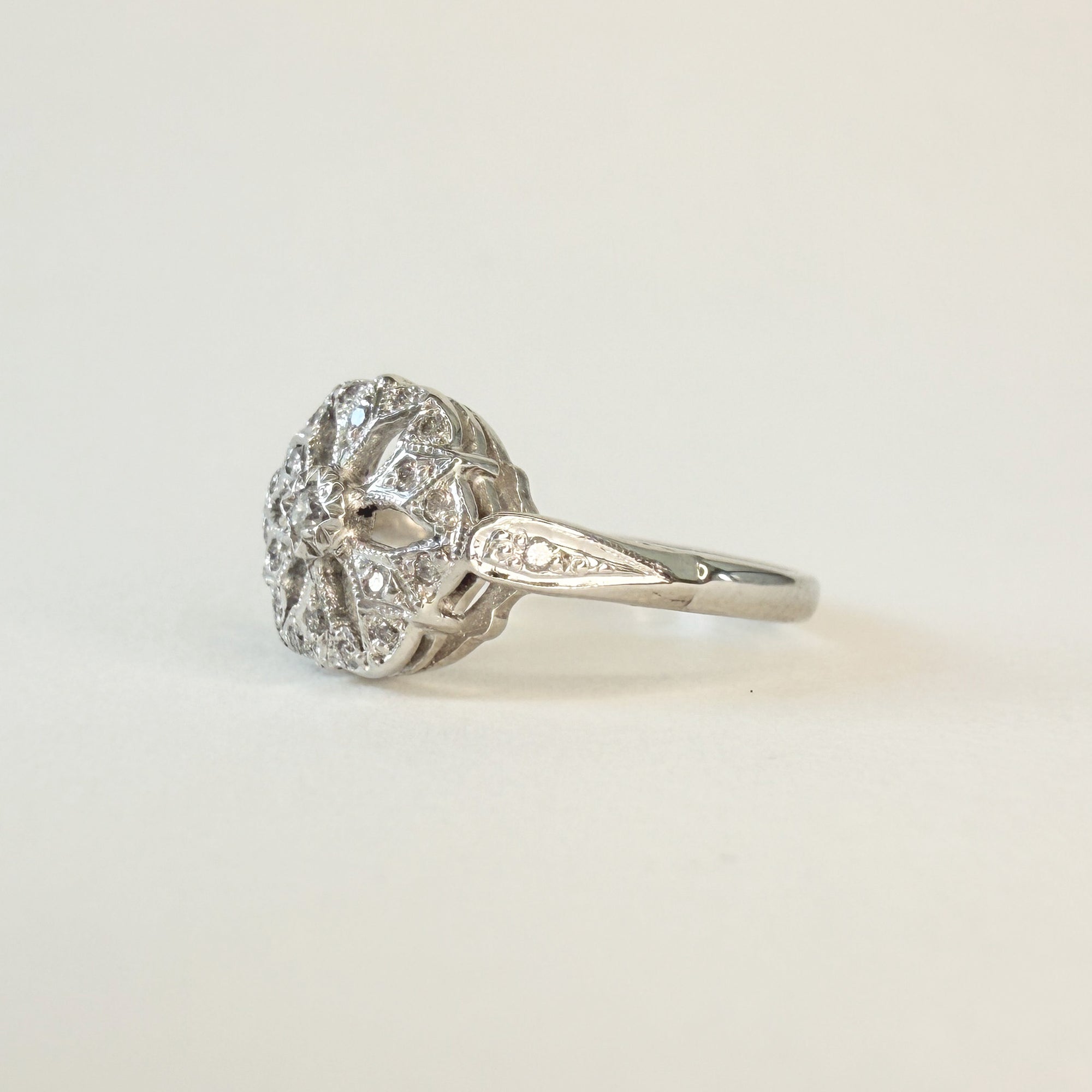 Bague en or gris 14 carats ajourée sertie de diamants taille brillant, motif délicat en forme de fleur ou de flocon, bijou raffiné et lumineux.