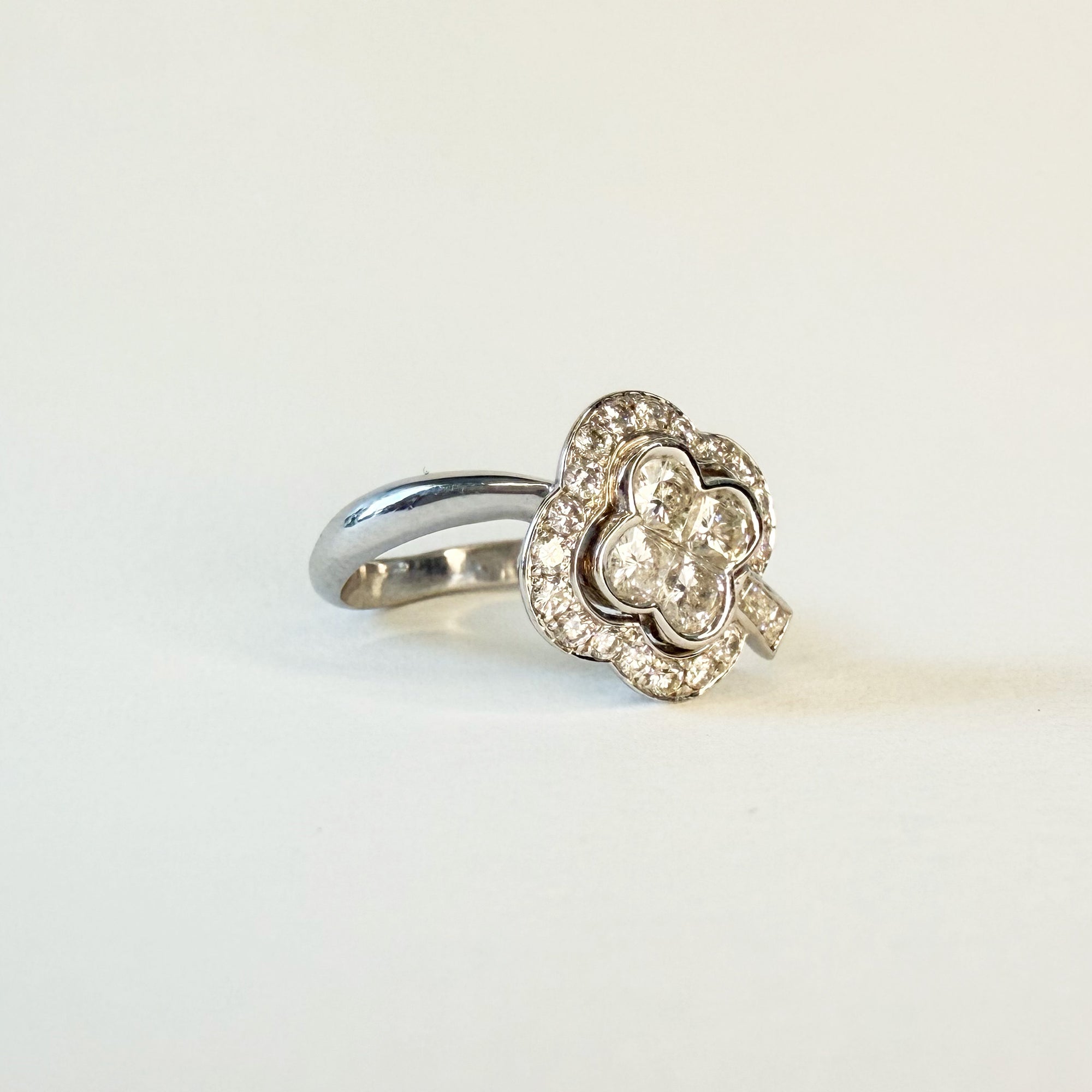 Bague en or blanc 18 carats sertie de diamants formant un motif de trèfle à quatre feuilles, bijou élégant et symbolique de la chance.