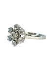 Bague en or gris 18 carats sertie de sept diamants taille brillant en serti griffe formant une fleur sur une monture ajourée, bijou raffiné et lumineux.