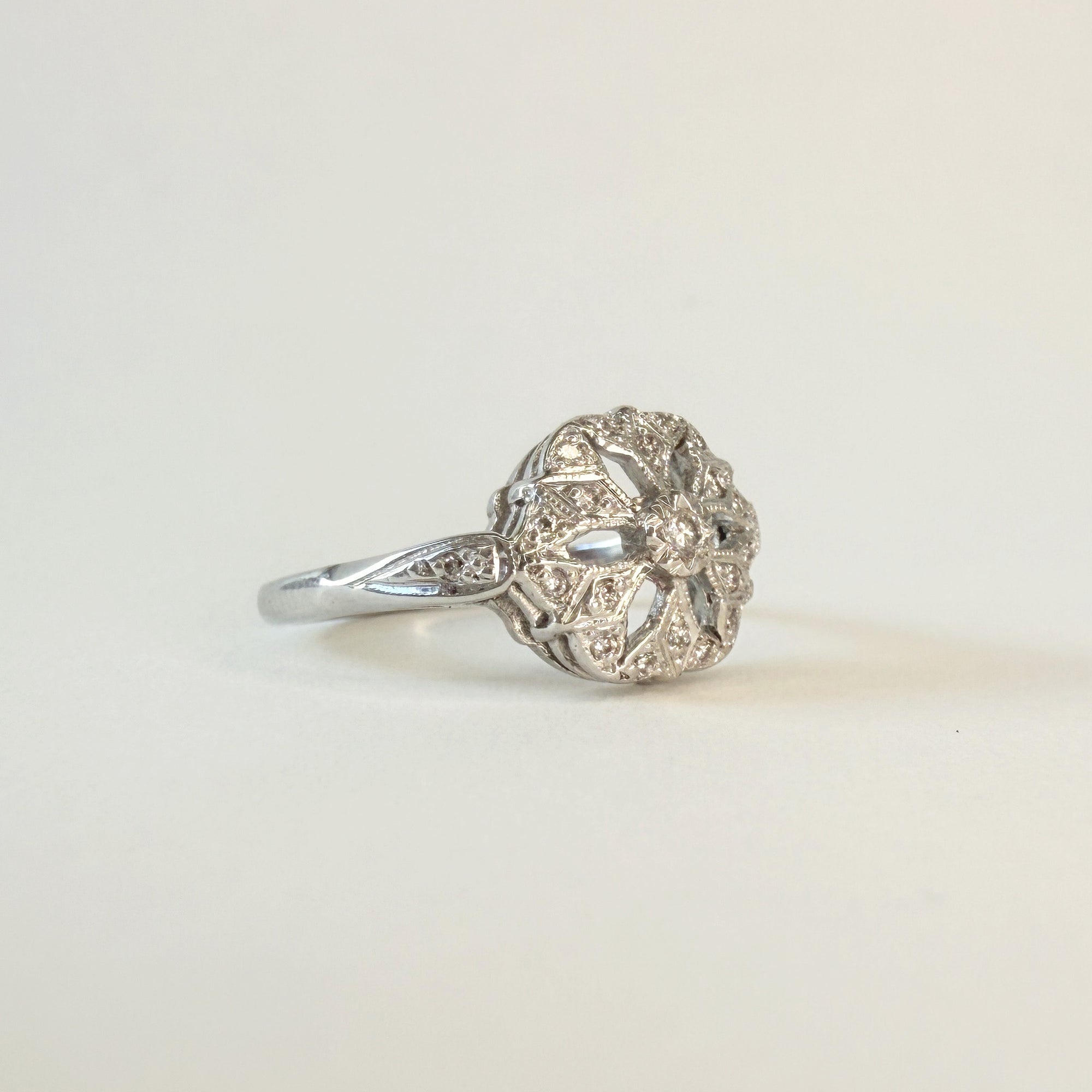 Bague en or gris 14 carats ajourée sertie de diamants taille brillant, motif délicat en forme de fleur ou de flocon, bijou raffiné et lumineux.