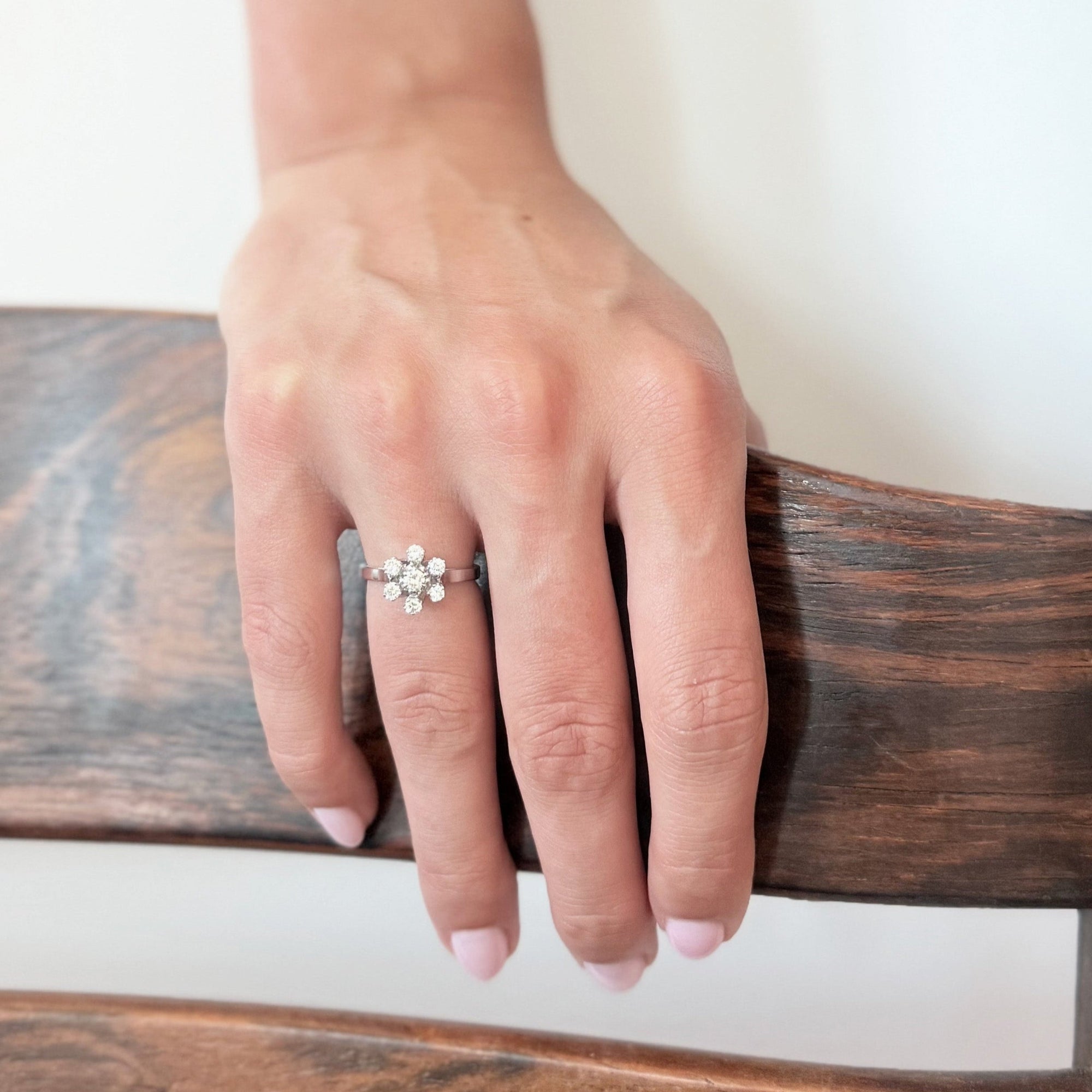 Bague en or gris 18 carats sertie de sept diamants taille brillant en serti griffe formant une fleur sur une monture ajourée, bijou raffiné et lumineux.