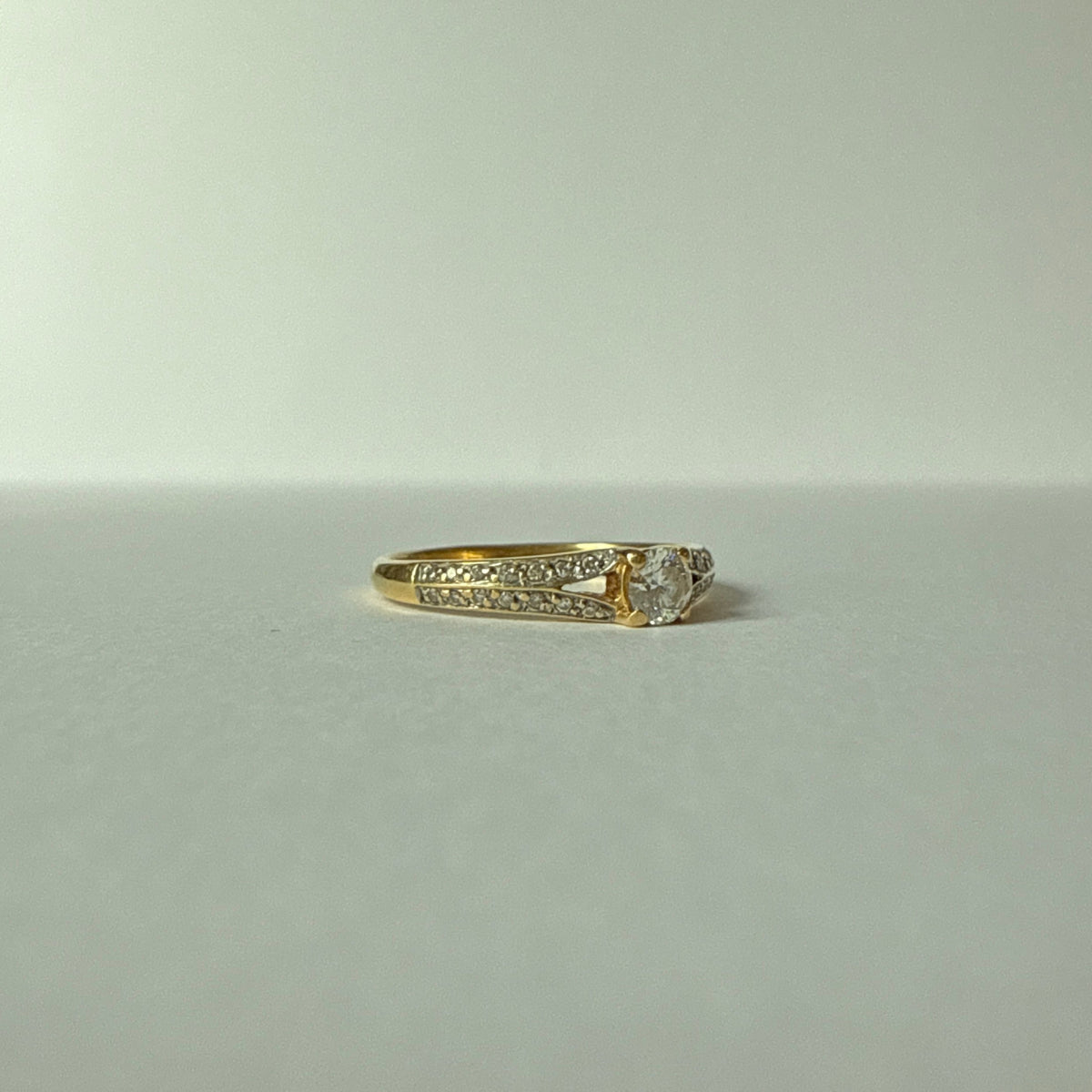 Bague en or jaune 18 carats avec diamant central de 0,20 carat et entourage de deux lignes de diamants, vue de trois quarts.