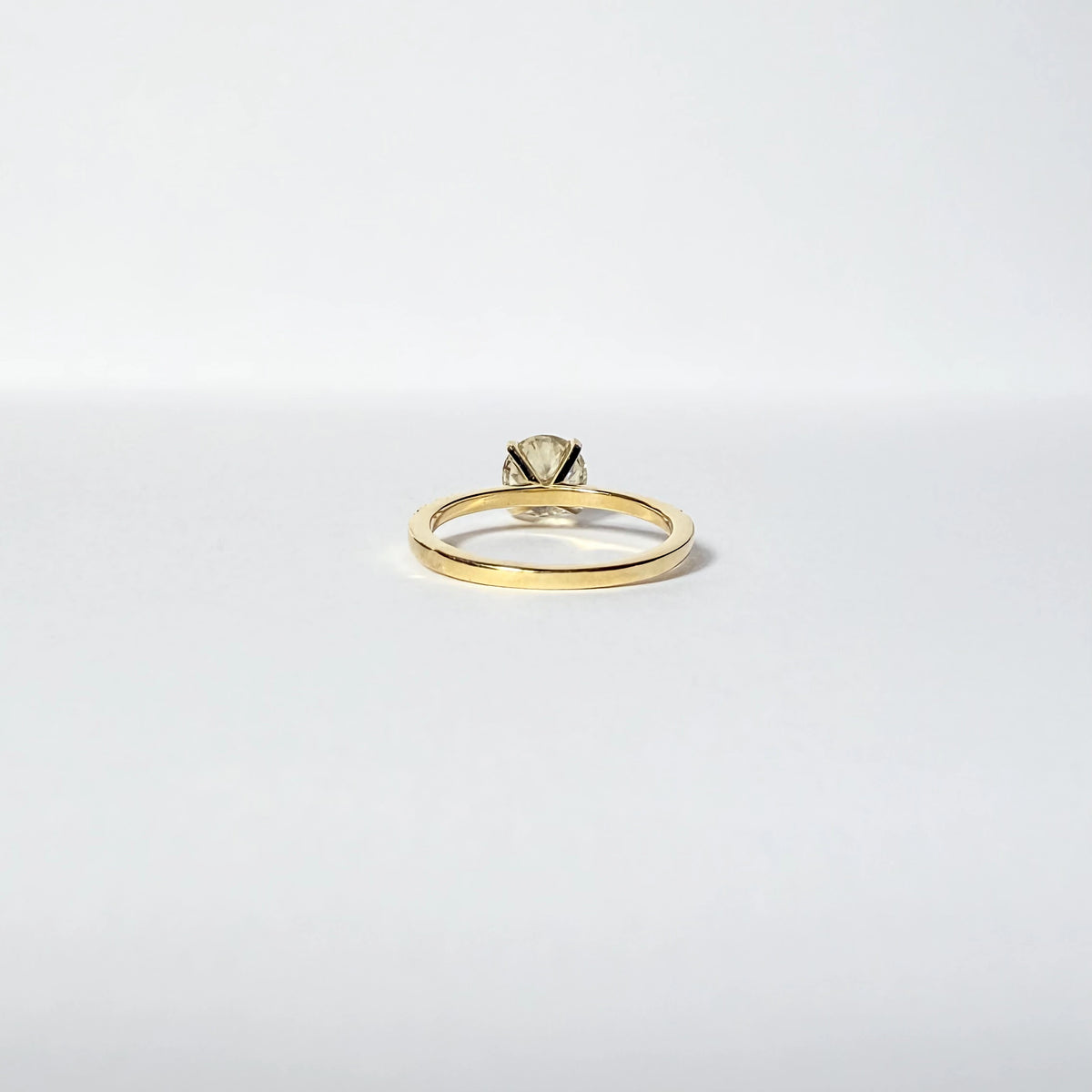 Bague de fiançailles en or jaune ornée d'un important diamant de 1.5 carats sur une monture en or et diamants, vue de dos 