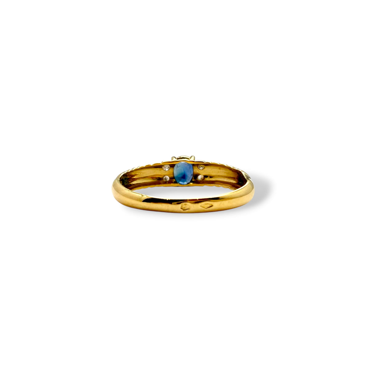 Vue de dessus d’une bague en or jaune ornée d’un saphir bleu ovale et de diamants sur une monture à godrons torsadés