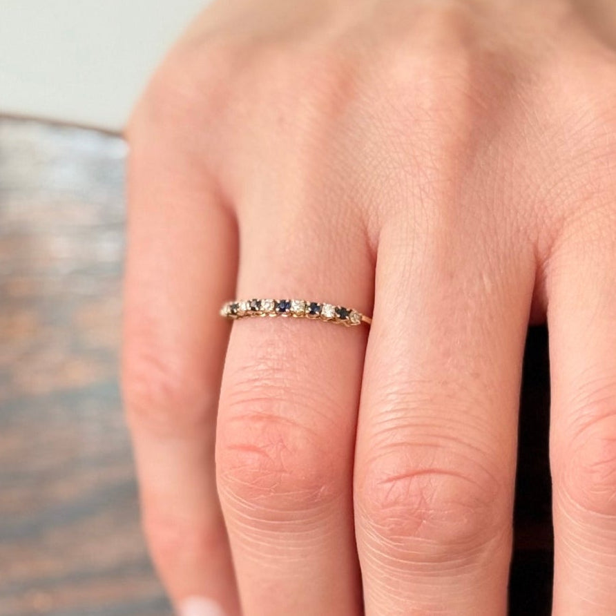 Bague demi-alliance en or jaune 18 carats avec diamants et saphirs naturels, portée au doigt