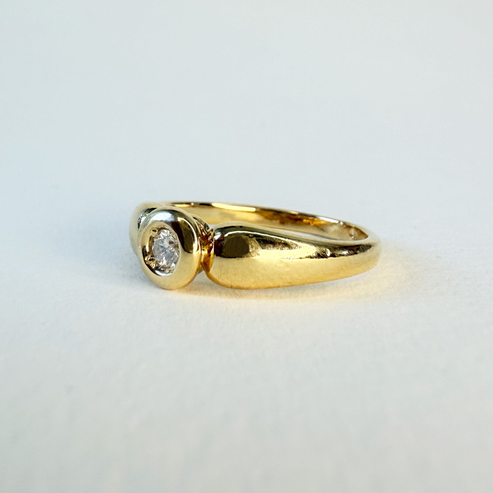 Bague solitaire en or jaune 18 carats sertie d’un diamant en serti clos d’environ 0,07 carat, bijou raffiné symbole d’amour éternel et d’engagement.