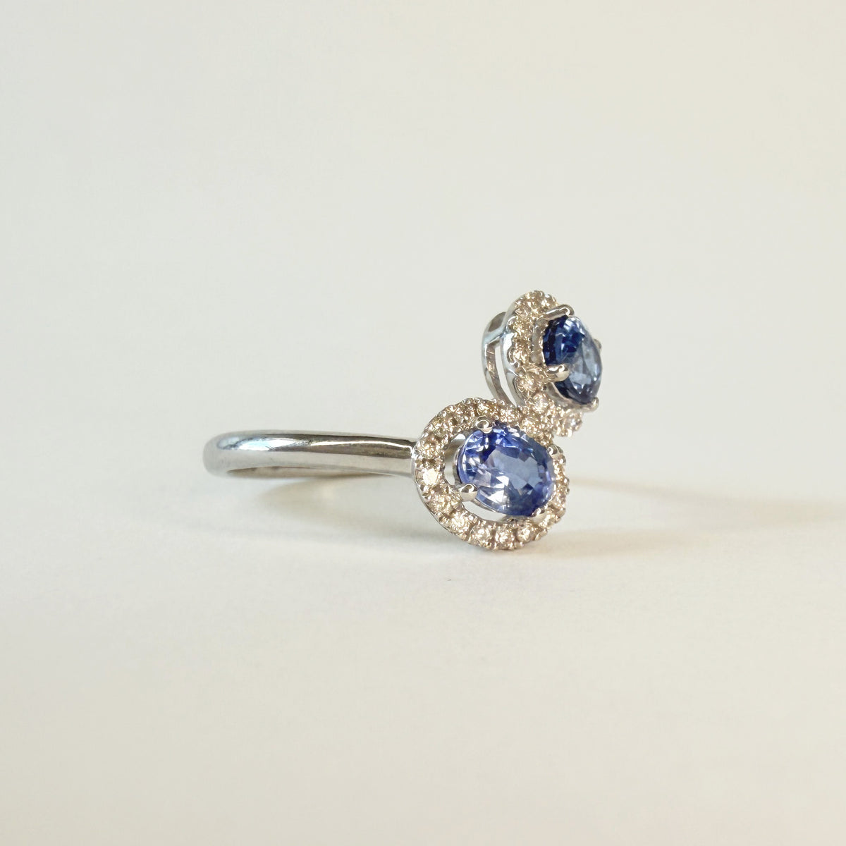 Bague ancienne en or gris 750 sertie de deux saphirs ovales d’environ 0,5 carat chacun et de diamants brillants, vue de profil.