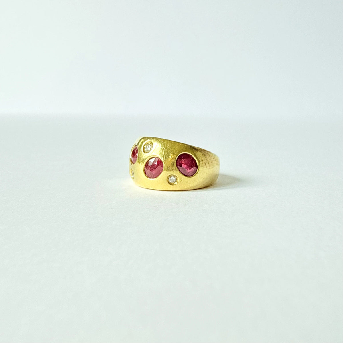 Bague vintage en or jaune 18 carats de forme bandeau ornée de jolis rubis rouges naturels non chauffés et de diamants.