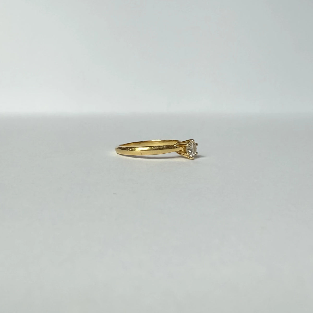 Bague solitaire en or jaune 18 carats ornée d'un diamant de 0,2 carats, vue de profil.