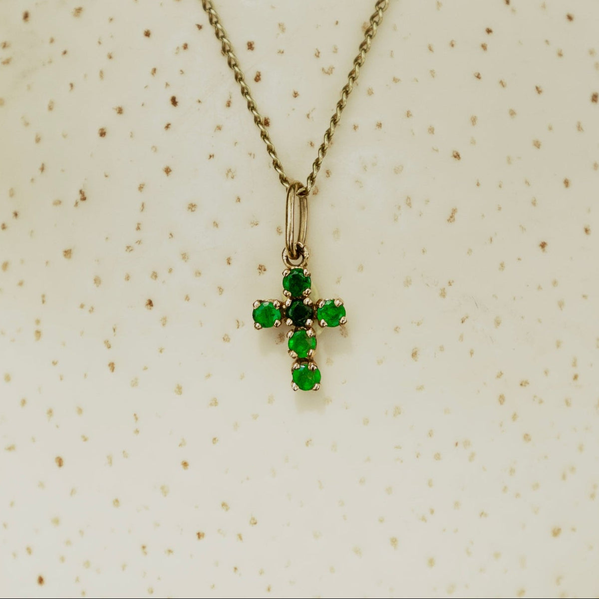 Pendentif croix en or ornée d’émeraudes, design élégant de la maison Labrune, visible avec détails raffinés.