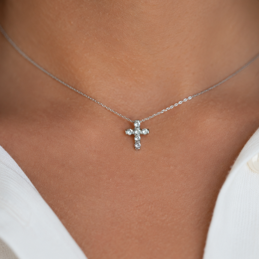 Pendentif croix en or gris 18 carats porté sur une chaîne.