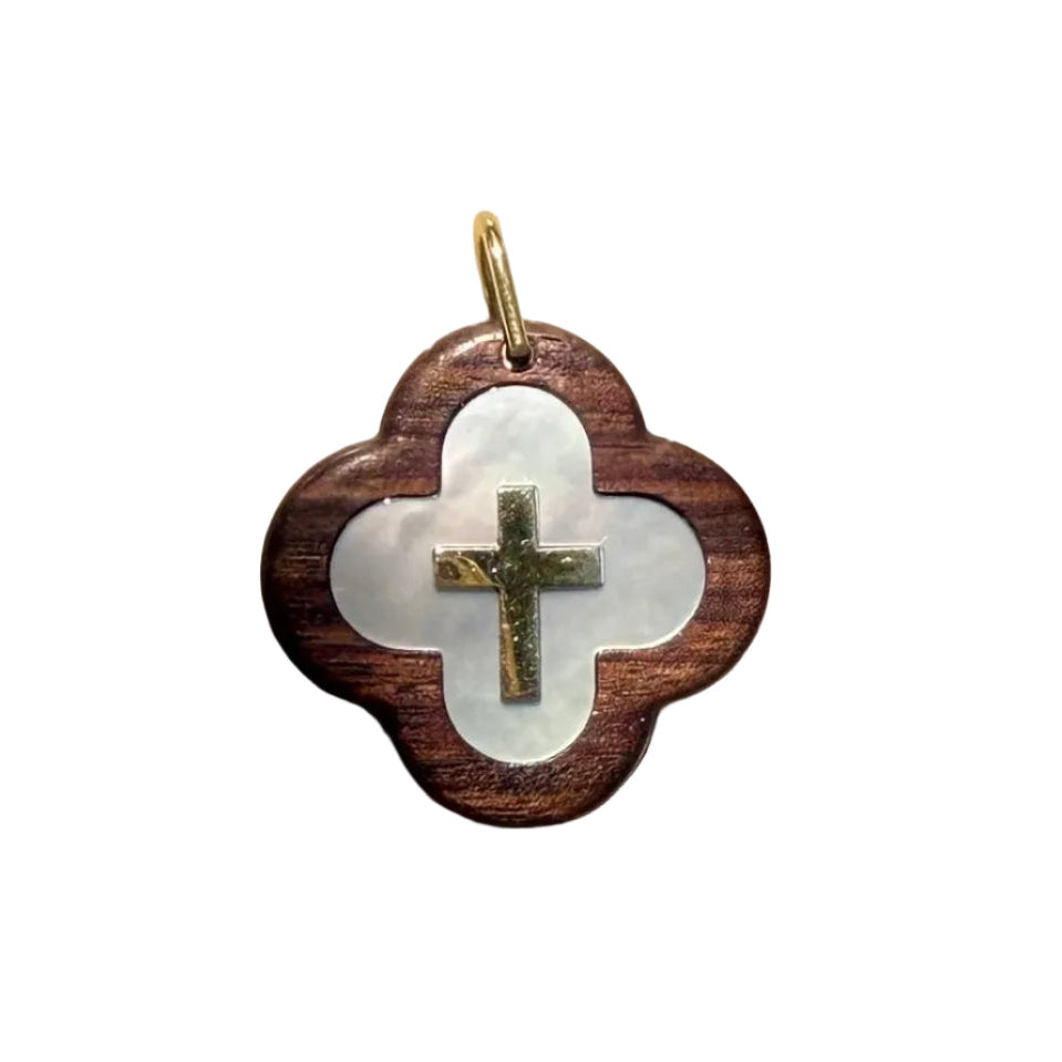 Pendentif croix en or et nacre avec design moderne, fabriqué par Maison Labrune, posé sur un fond en bois naturel.