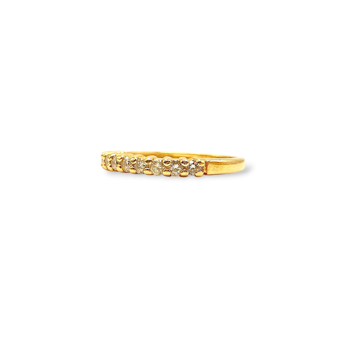 Détail du serti grain d’une demi-alliance en or jaune 18 carats, mettant en valeur une rangée de petits diamants.