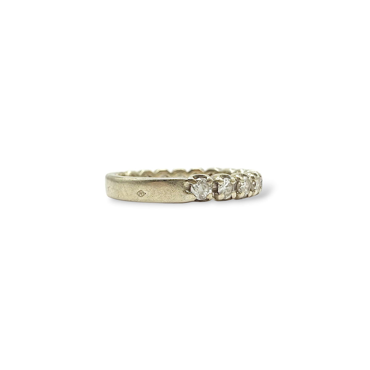 Détail du serti griffes d’une demi-alliance en or blanc 18 carats, mettant en valeur une rangée de diamants taille moderne.