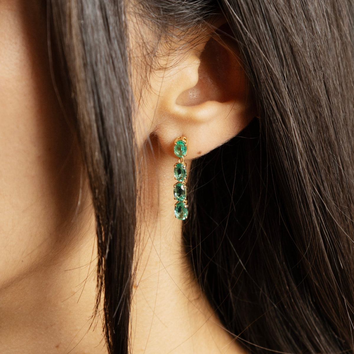 Boucles d’oreilles pendantes en or jaune 18 carats et émeraudes naturelles, longueur d’environ 27 mm, pour une allure élégante et colorée.
