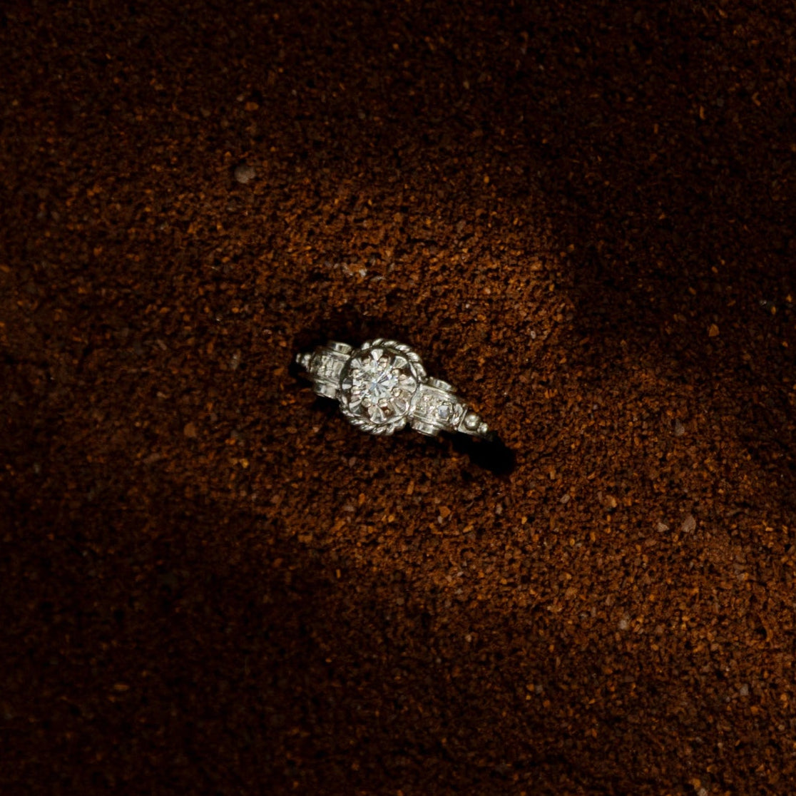 Bague ancienne en or blanc 18 carats ornée d’un diamant taille brillant d’environ 0,1 carat, monture à volutes et torsades inspirée de l’Art Déco, bijou élégant des années 1950.