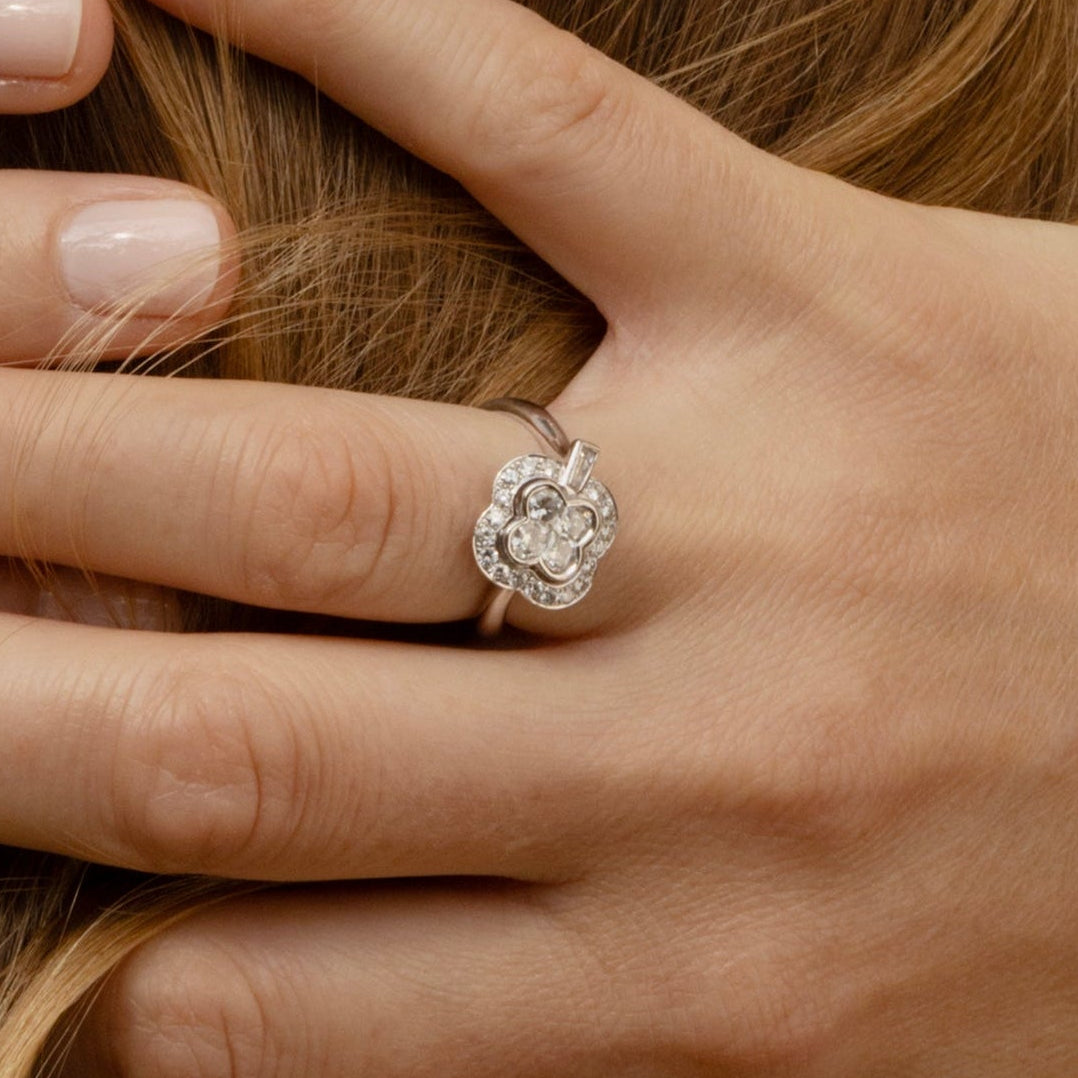 Bague ancienne en or 18k et diamants formant un trèfle à quatre feuilles, portée sur un doigt, idéal pour des fiancailles ou un cadeau d'exception.