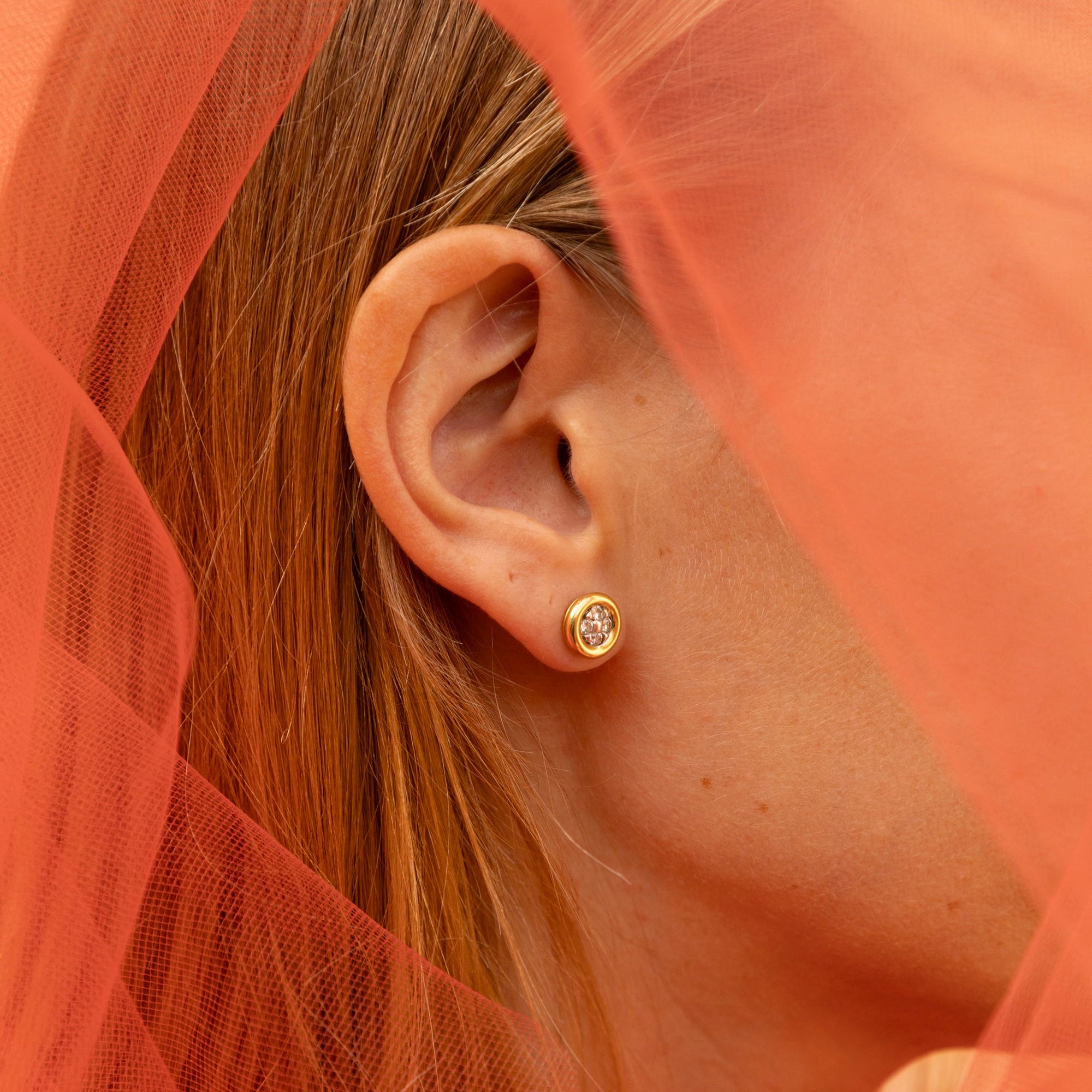 Clous d'oreilles en or jaune 18 carats et diamants portés sur une oreille.