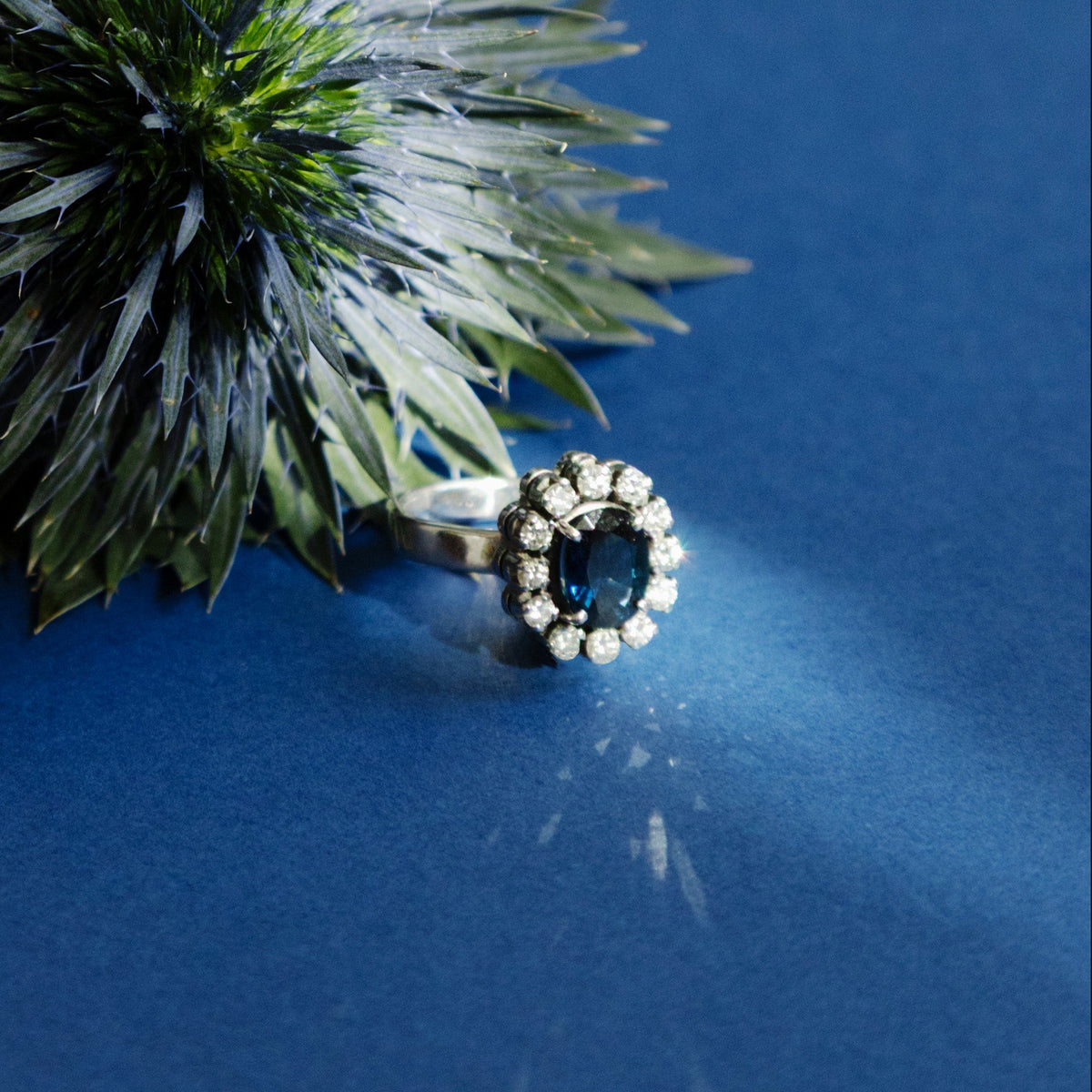Bague marguerite en or blanc 18 carats sertie d'un saphir naturel ovale entouré de 12 diamants,, photo artistique.