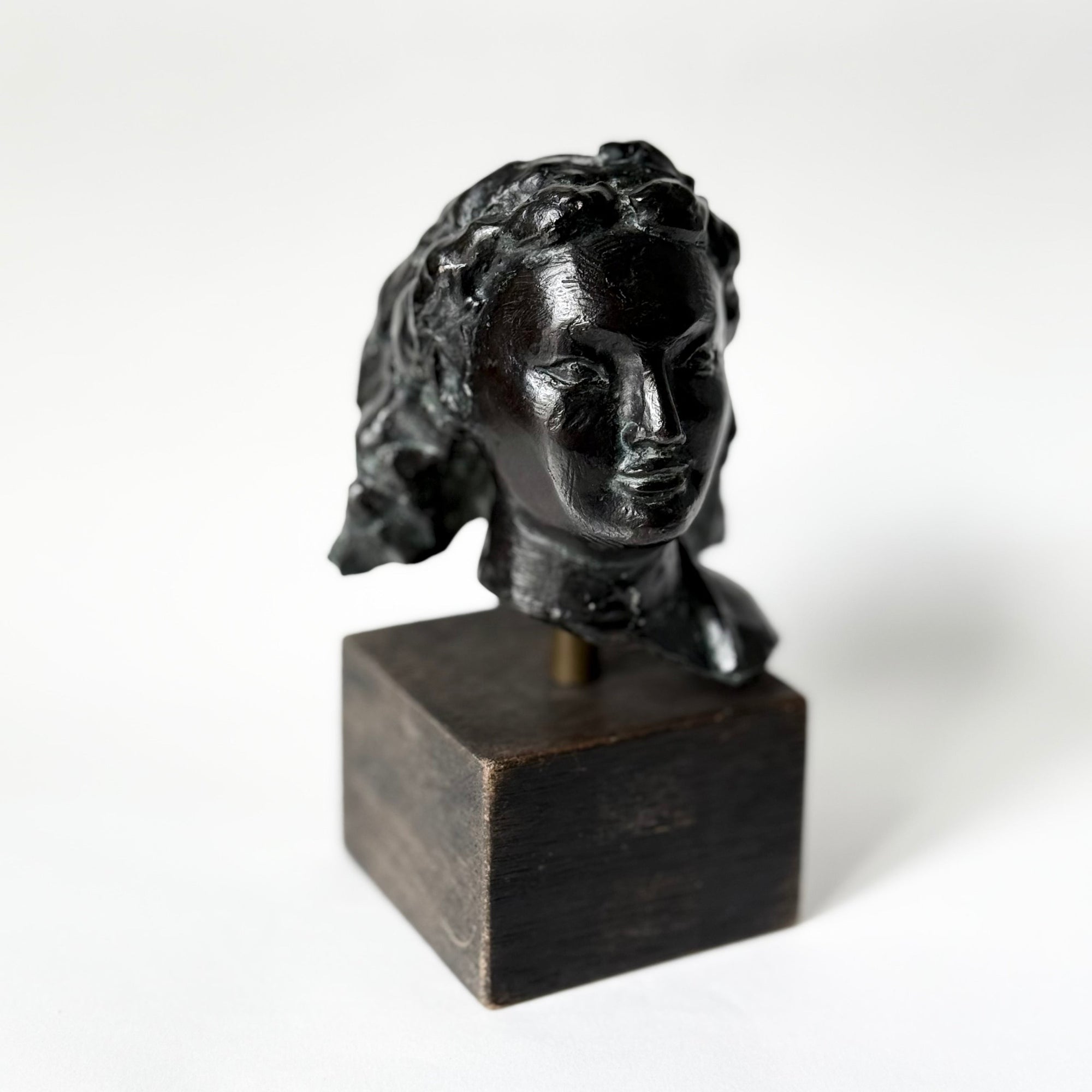 Sculpture en bronze représentant un portrait de femme, tête sculptée aux traits doux et expressifs, patine sombre nuancée, reposant sur un socle en bois, œuvre du sculpteur français Maurice Guillaume (1920–2015).