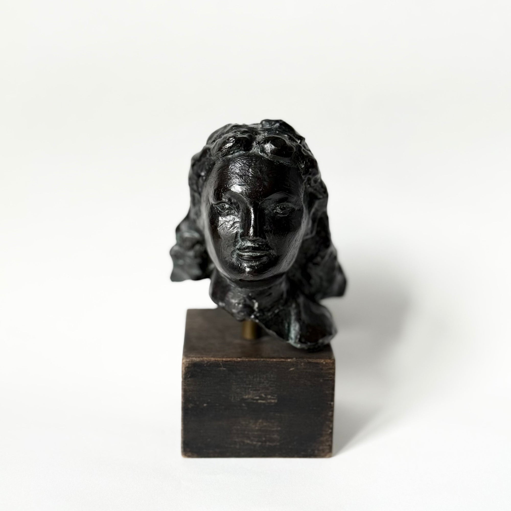 Sculpture en bronze représentant un portrait de femme, tête sculptée aux traits doux et expressifs, patine sombre nuancée, reposant sur un socle en bois, œuvre du sculpteur français Maurice Guillaume (1920–2015).