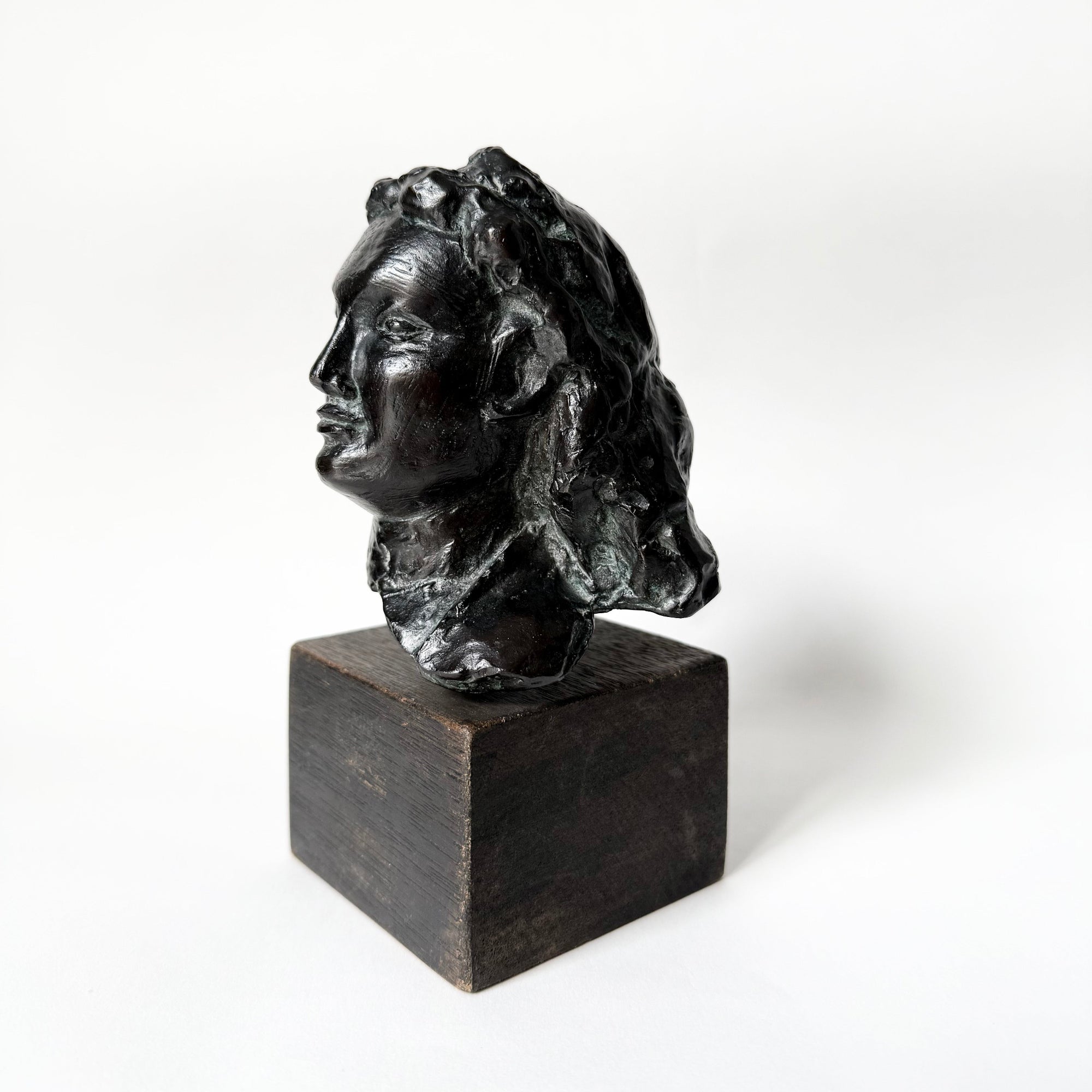Sculpture en bronze représentant un portrait de femme, tête sculptée aux traits doux et expressifs, patine sombre nuancée, reposant sur un socle en bois, œuvre du sculpteur français Maurice Guillaume (1920–2015).