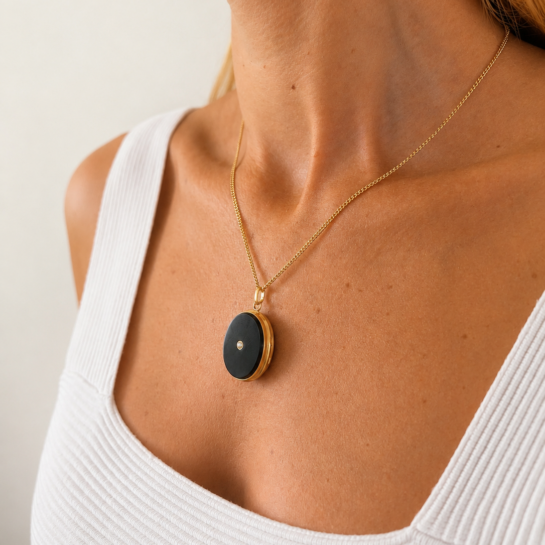 Médaillon porte-souvenir ancien ovale en or jaune 18 carats, orné d'un onyx noir et d'une perle centrale, bijou français vers 1910-1920.