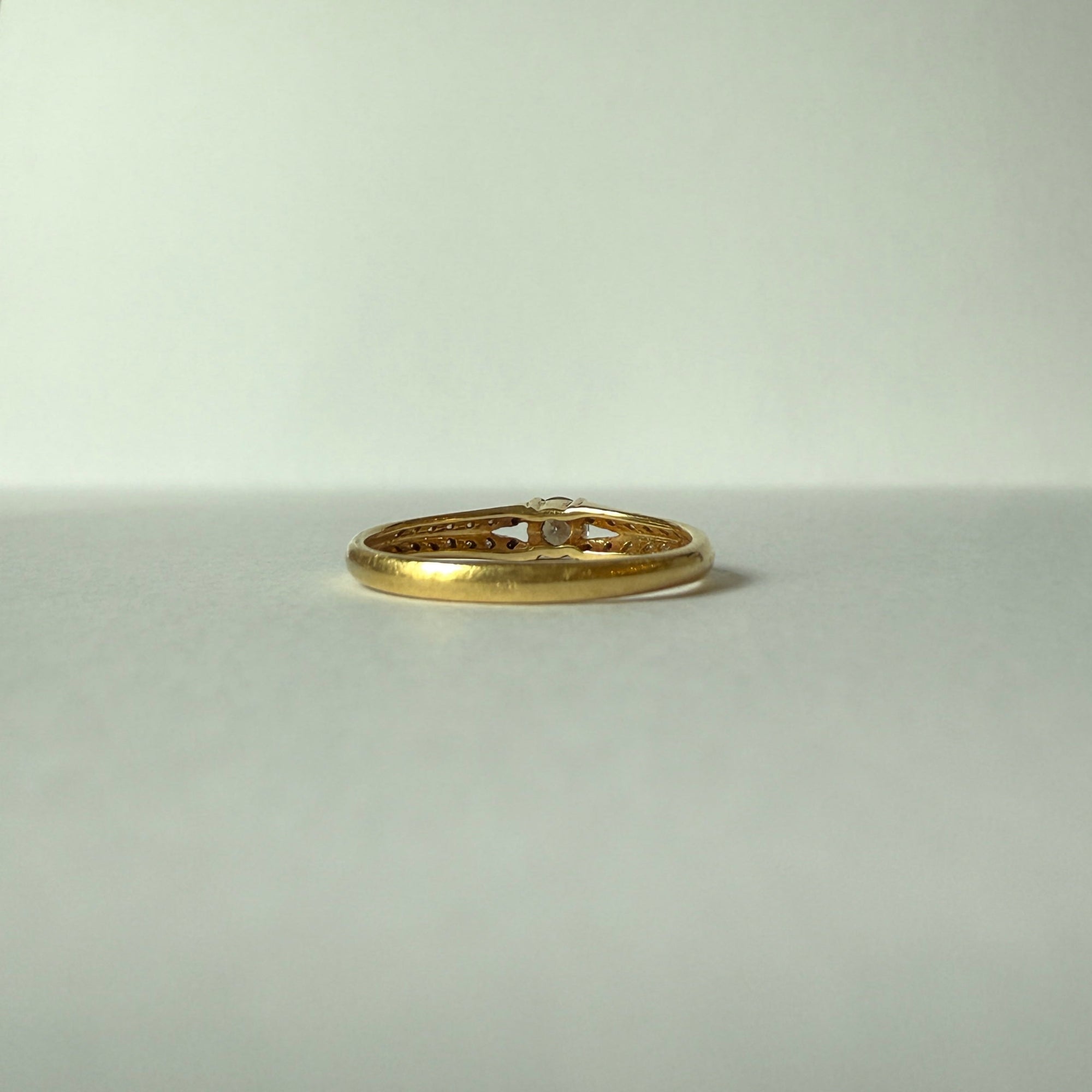 Détail de la monture ajourée en or jaune 18 carats d’une bague solitaire ornée de diamants.