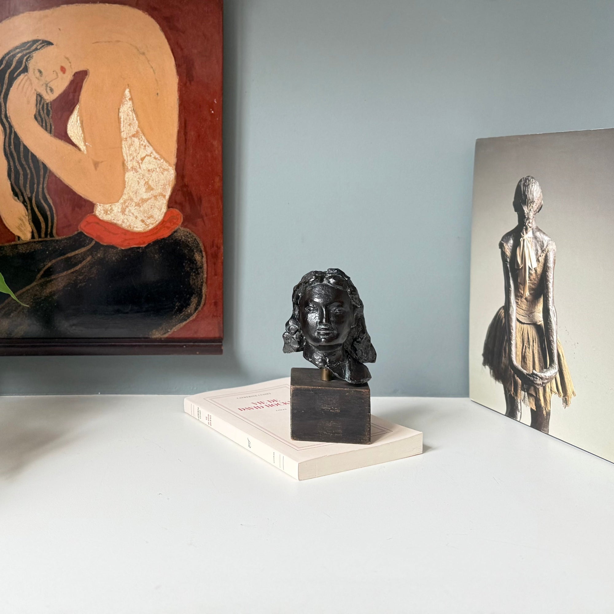 sculpture portrait de femme en bronze devant un livre de degas et une laque vietnamienne représentant une femme à sa toilette avec un influence de Matisse. 